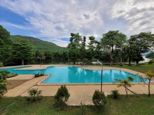 a large swimming pool in a field with trees at Aekpailin River Kwai Resort in Kanchanaburi City