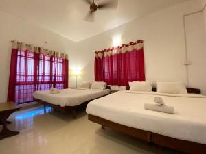 twee bedden in een kamer met rode gordijnen bij Le Royce Private Villa in Pondicherry