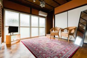 a living room with a television and chairs and a rug at Shikano Resort in Nara