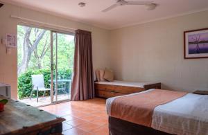 a bedroom with two beds and a sliding glass door at The Station at El Questro in Kununurra
