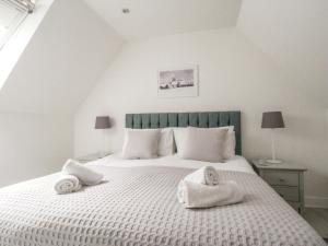 a bedroom with a large white bed with towels on it at Meadow View Barn in Wareham
