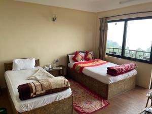a hotel room with two beds and a window at Hotel Nagarkot Holiday Inn in Nagarkot
