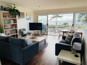 a living room with two couches and a table at The Esplanade Holiday Home in Indented Head