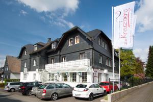 una gran casa negra con coches aparcados delante en Hotel zum Kreuzberg, en Winterberg