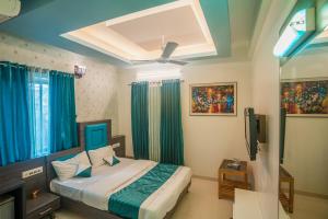 Schlafzimmer mit einem Bett mit blauen Vorhängen und einem TV in der Unterkunft Hotel New Panchratna in Ahmednagar