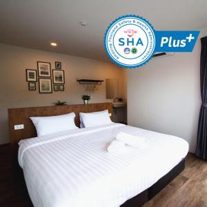 a bed with white sheets and a sign that says shha plus at The Arbern Hotel x Bistro - SHA Extra Plus in Phuket Town