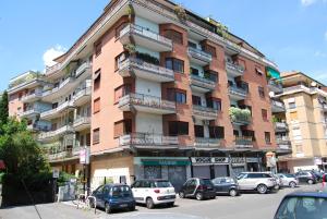 un gran edificio de ladrillo con coches estacionados frente a él en Residenza Flaminia, en Roma
