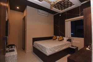 ein Schlafzimmer mit einem Bett mit gelben Kissen in der Unterkunft Hotel Atlantis in Kumbakonam