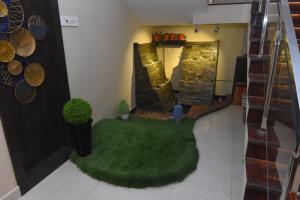 a living room with a green rug and stairs at Hotel Lynx in Kumbakonam +1 photo