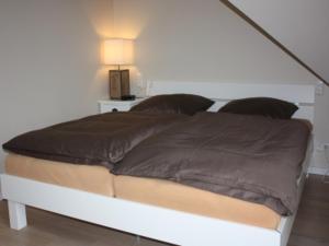 a bed in a white room with at BadeWerk Appartements in Neuharlingersiel