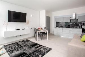 a white living room with a table and a kitchen at La Torre House in Santa Teresa Gallura