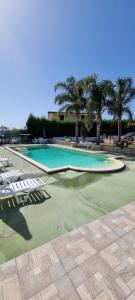 une grande piscine avec des chaises et des palmiers dans l'établissement Villa Maria con piscina e giardino privato, à Santa Maria