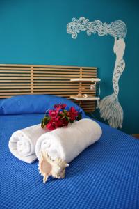 1 dormitorio azul con 1 cama con toallas y flores en B&B Vivere il Mare, en San Vito lo Capo