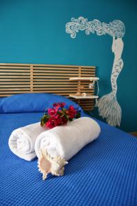 a blue bedroom with a bed with towels and flowers at B&B Vivere il Mare in San Vito lo Capo