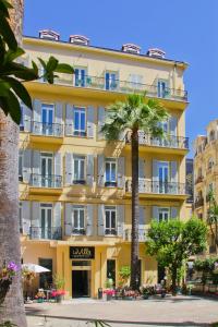 un bâtiment jaune avec un palmier devant lui dans l'établissement Hotel La Villa Nice Promenade, à Nice