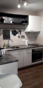 La cuisine est équipée de placards blancs, d'un évier et d'une cuisinière. dans l'établissement Residentie Spinnaker, à Blankenberge