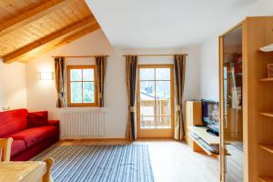a living room with a red couch and a tv at Villa Anna in Siusi