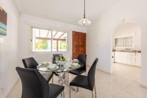 a dining room with a glass table and black chairs at Bungalow Casa Bella by Ezoria Villas in Coral Bay