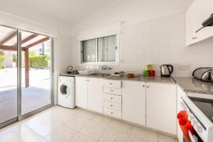 a kitchen with white cabinets and a washer and dryer at Bungalow Casa Bella by Ezoria Villas in Coral Bay