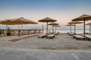 NISSEA Boutique Hotel في كاردامينا: مجموعة من المقاعد والمظلات على الشاطئ