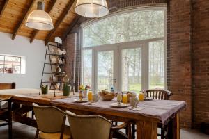 a dining room with a table and a large window at B&B Grevenberg in Oosterhesselen