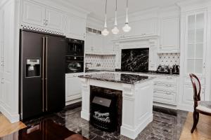 a kitchen with white cabinets and a black refrigerator at Apartament Royal in Łomża
