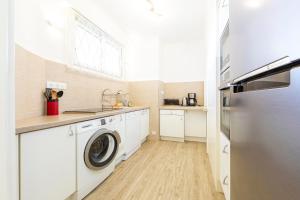 una cocina blanca con lavadora y secadora. en Fully equipped appartment 105 m2 clear view on the sea and californie hills, en Cannes