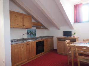 eine Küche mit Holzschränken, Spüle und Tisch in der Unterkunft Hotel B&B Francolini in Folgaria