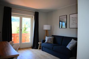 a living room with a blue couch and a window at Forest Mountain Apartment in Bad Kleinkirchheim