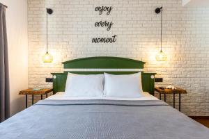 una cama con una cabecera verde y un cartel que lee cada momento feo en The Poyz Hotel Bodrum en Gumbet
