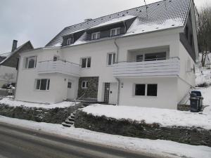 una casa blanca con nieve en el suelo en Ferienhäuser Bergfreiheit, en Winterberg