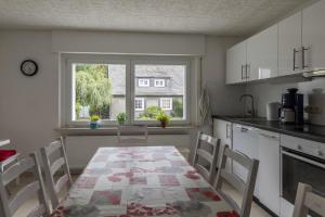 une cuisine avec une table et des chaises ainsi qu'une fenêtre dans l'établissement Ferienhäuser Bergfreiheit, à Winterberg