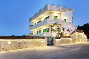 a large white building with a stone wall at Achilleas Apartments with Sea View in Kolymvari