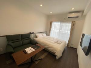 Habitación con cama, sofá y TV. en HOTEL GranLeaf Miyakojima, en Isla Miyako