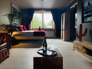 Ol folle spa في مالميدي: غرفة مع سرير وطاولة مع زجاجة من النبيذ