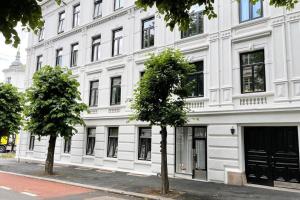 a white building with two trees in front of it at Nordic Host - Frogner - Well appointed 2 Bedroom in Lovely West Side Neighborhood in Oslo