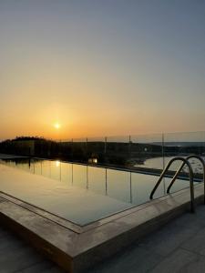 a swimming pool with the sunset in the background at Hotel VIU57 in Mellieħa