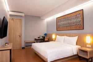 1 dormitorio con 1 cama blanca grande y TV en BATIQA Hotel Jayapura en Jayapura