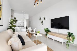 sala de estar con muebles blancos y TV de pantalla plana en Lanzarote Blue Senator, en Costa Teguise