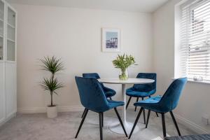 uma sala de jantar com uma mesa e cadeiras azuis em Penleys Apartment em York