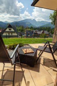 a table and chairs on a patio with mountains in the background at Rent like home - Ubocz 1D in Zakopane