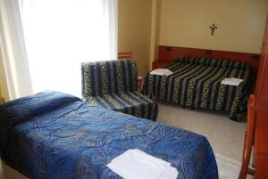 a hotel room with two beds and a chair at Hotel Il Chierichetto in San Giovanni Rotondo
