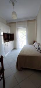 a bedroom with a bed and a kitchen with a window at Nearby the sea in Asprovalta