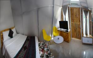 a bedroom with a bed and a tv and a yellow chair at GSV Cottage Sharia in Bogor