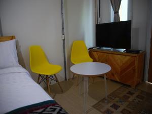 ボゴールにあるGSV Cottage Shariaのベッドルーム1室(黄色い椅子2脚、テーブル、テレビ付)