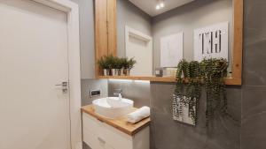 ein Badezimmer mit einem weißen Waschbecken und einem Spiegel in der Unterkunft APARTAMENTY NADJEZIORNE z tarasem na dachu in Lyck