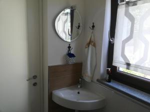een badkamer met een wastafel, een spiegel en een raam bij Grazioso monolocale - Borgo Malan, Luserna S. G. in Luserna San Giovanni