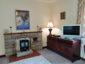 een woonkamer met een televisie en een open haard bij The Maid's House in Lanark