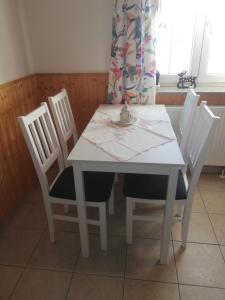 a white dining room table with four chairs and a table and a window at Ubytování Maxa in Špičák