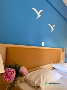 a bed with a vase of flowers and birds on a blue wall at Thalassenia Studios in Hanioti